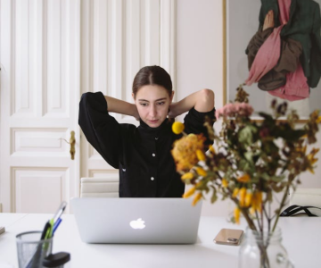 Accueil AV Freelance femme en chemisier noir assise devant un ordinateur portable argenté